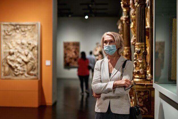 Mulher visitando museu usando máscara antivírus