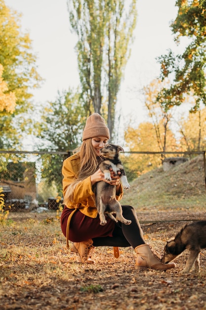 Mulher voluntária que ama o animal de estimação brinca com cachorrinhos sem-teto no parque de outono, momentos autênticos de alegria