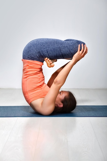 Mulher yogini esportiva pratica ioga invertida asana Urdhva padmasana levantou pose de lótus