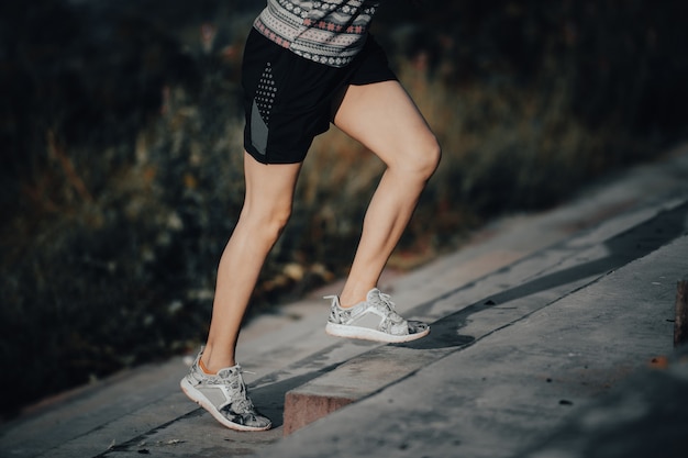 Mulher younh corre no verão na cidade na corrida matinal fundo da escada