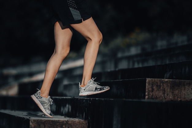 Mulher younh corre no verão na cidade na corrida matinal fundo da escada