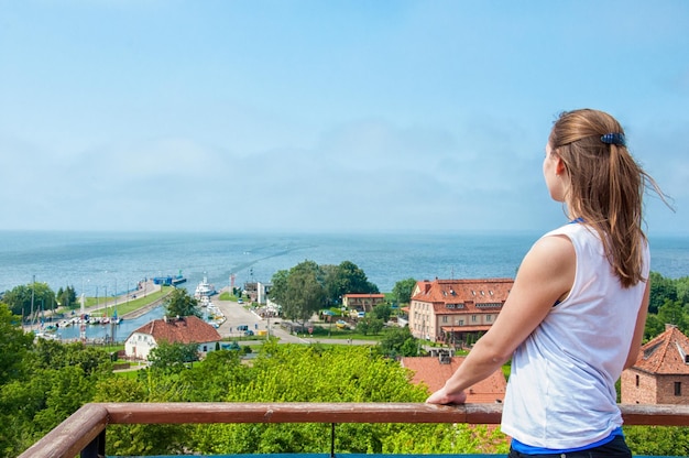 Mulher Ypung olhando para Bay frombork polônia Vista pitoresca na pequena cidade e marina da torre superior