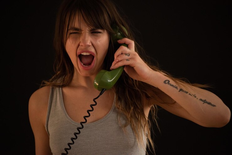 Foto mulher zangada falando por telefone contra um fundo preto