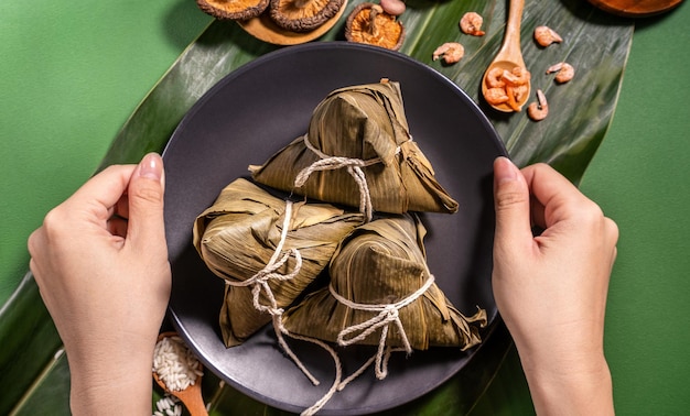 Mulher Zongzi comendo bolinhos de arroz cozido no vapor na comida de fundo de mesa verde no conceito duanwu do festival do barco dragão fechar espaço de cópia vista superior plana lay