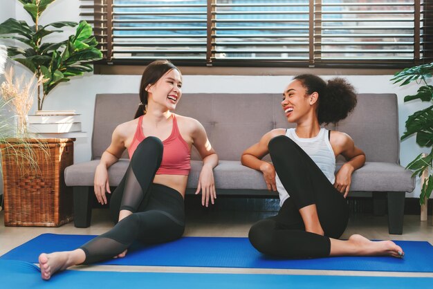 Mulheres adultas jovens relaxando depois de fazer ioga conversando juntas se exercitando em casa com amigos esporte e conceito de recreação