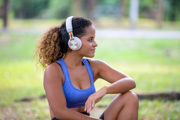 mulheres afro-americanas de raça mista sentado no parque com fone de ouvido