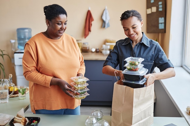Mulheres afro-americanas desempacotando pedido de entrega de comida em casa