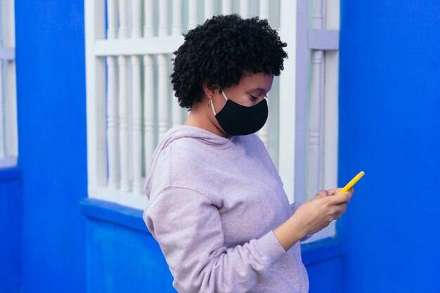 Mulheres afro com protetor de máscara usando um celular