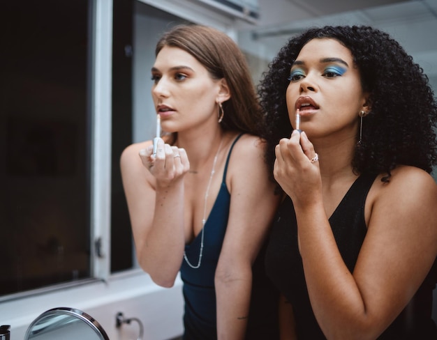 Mulheres amigas e cosméticos no espelho no banheiro para beleza, bem-estar e maquiagem à noite juntos Menina negra e modelo com estética de batom escuro e suporte para cosméticos na festa