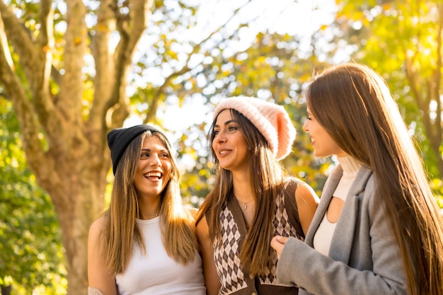 Mulheres amigas sorrindo em um parque no outono com chapéus de lã na moda estilo de vida do outono