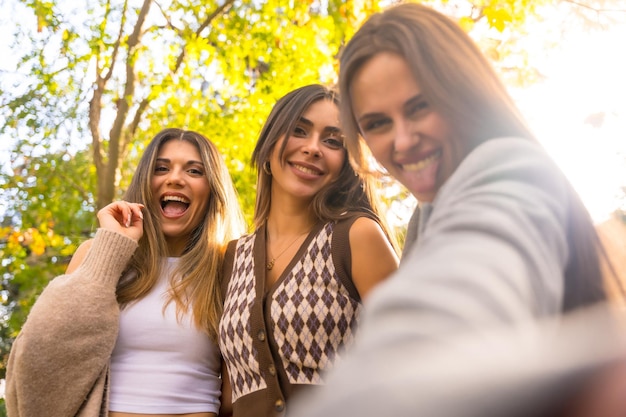 Mulheres amigas sorrindo em um parque no outono tomando um estilo de vida selfie no outono