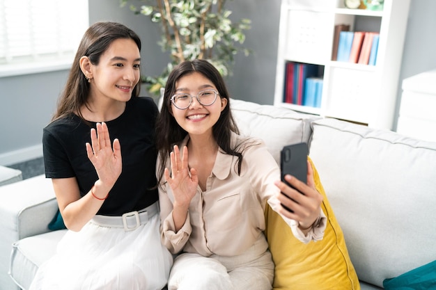 Mulheres asiáticas atraentes sentam-se no sofá em novos colegas de apartamento estudantes garota com óculos