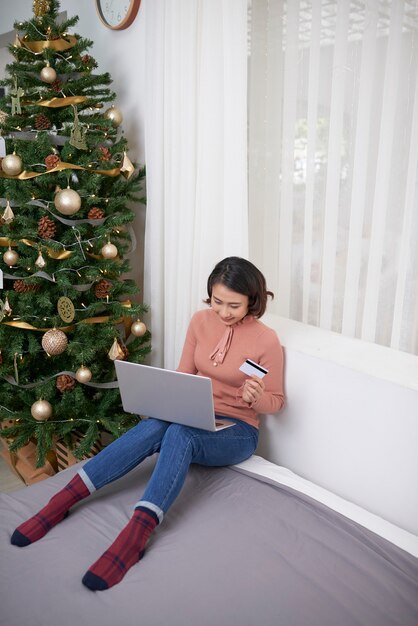 Mulheres asiáticas compram online usando cartão de crédito, ela está na cama