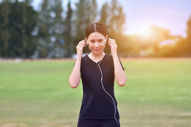 Mulheres asiáticas de beleza ouvindo música quando exercitar manhã de execução no parque da cidade