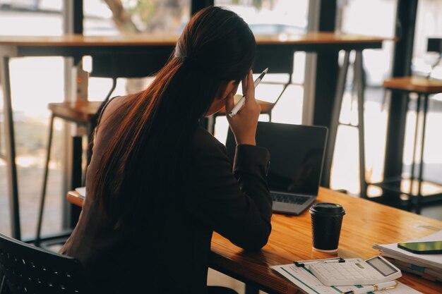 Mulheres asiáticas estão estressadas enquanto trabalham no laptop mulher de negócios asiática cansada com dor de cabeça no escritório sentindo-se doente no trabalho espaço de cópia