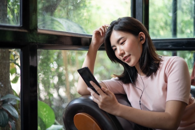 Mulheres asiáticas estão trabalhando e ouvindo música em telefones celulares.