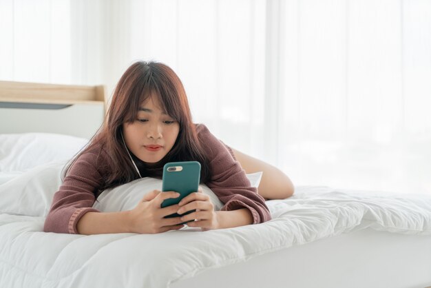 Mulheres asiáticas jogando smartphone na cama