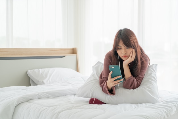 Mulheres asiáticas jogando smartphone na cama