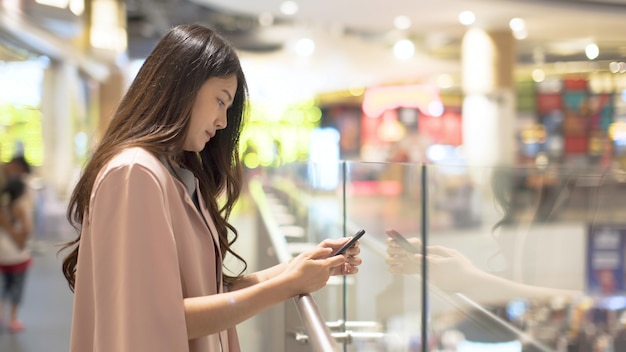 Mulheres asiáticas, jogando telefones celulares, em, shopping centers