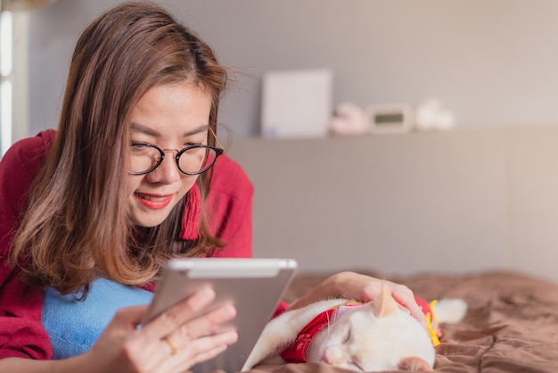 Mulheres asiáticas lendo na cama com um gato em casa