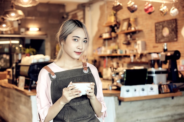 Mulheres asiáticas, segurando a xícara de café no café