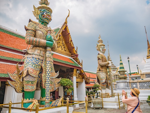 Mulheres asiáticas sêniors fazem uma pose tailandesa de saudação ao gigante no templo de wat phrakaew na cidade de Bangkok, Tailândia.