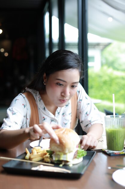 Mulheres asiáticas sorrindo e feliz e gostava de comer hambúrgueres no café e restaurante
