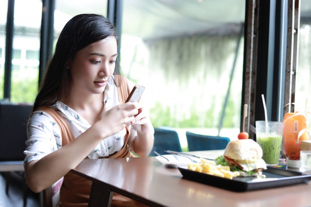 Mulheres asiáticas tirando foto de hambúrgueres e gostava de comer no café e restaurante na hora de relaxar