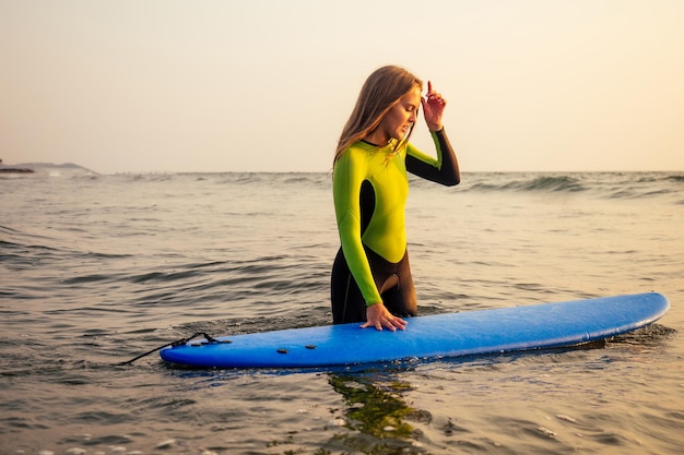 Mulheres ativas com prancha de surf desfrutam de esportes aquáticos nas férias de férias. Menina esportiva no instrutor de escola de surf de windsurf. turista modelo feminina em uma roupa de mergulho na praia do Oceano Índico