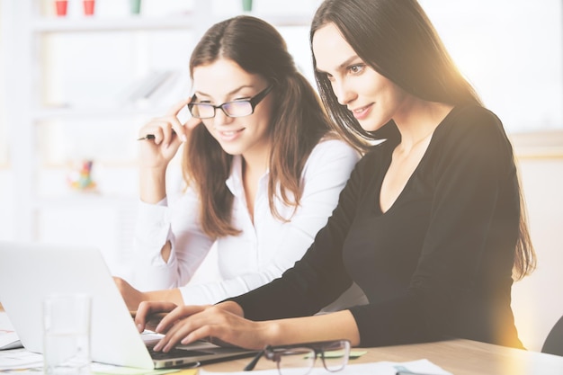 Mulheres atraentes usando laptop no local de trabalho