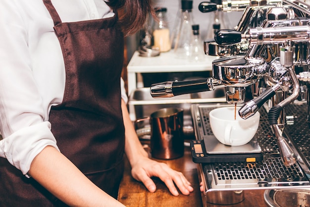 Mulheres barista usando máquina de café para fazer café no café