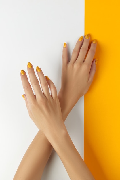 Mulheres bem cuidadas com um design moderno de unhas em fundo laranja e branco