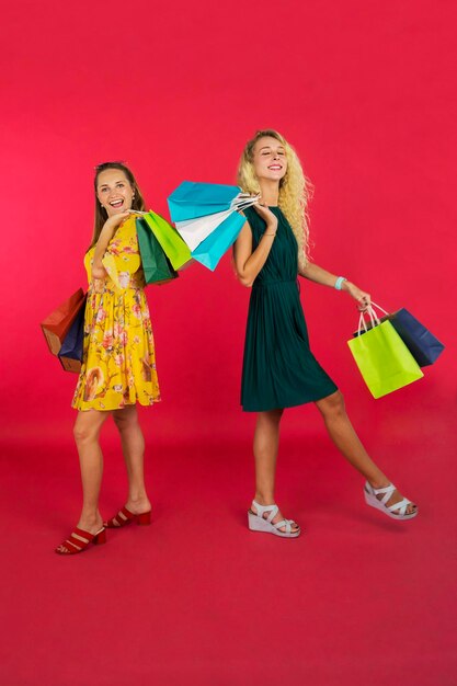 Mulheres bonitas a carregar sacos de compras e a sorrir.
