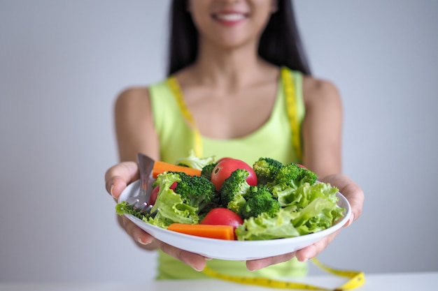 Mulheres bonitas asiáticas estão felizes em comer legumes de salada.