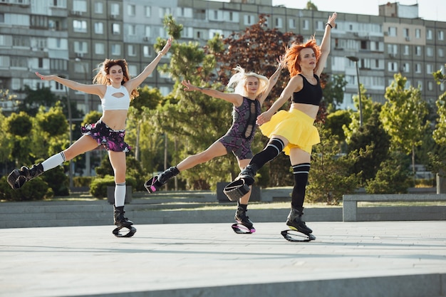 Mulheres bonitas em roupas esportivas pulando de canguru pulando sapatos na rua