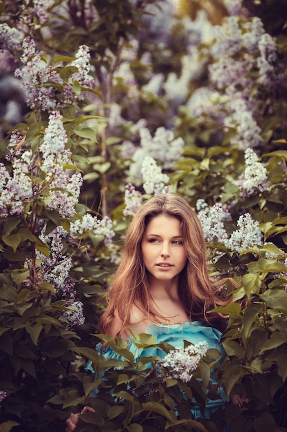 Mulheres bonitas que apreciam o jardim lilás, jovens mulheres com as flores no parque verde. alegres adolescentes caminhando ao ar livre. cor do estilo de luz suave