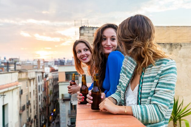 Mulheres bonitas que apreciam uma cerveja em um telhado em Barcelona