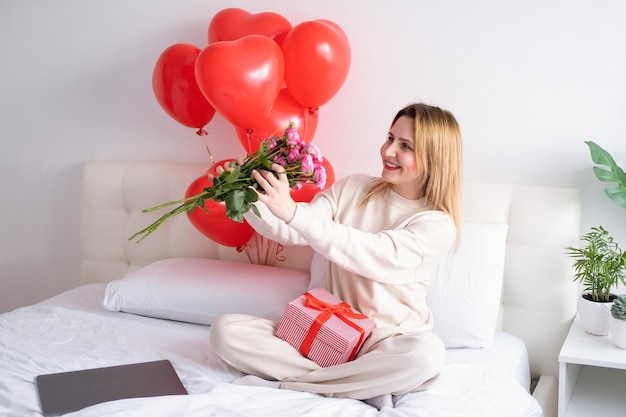 Mulheres bonitas segurando buquê de rosas na cama comemorando o dia dos namorados
