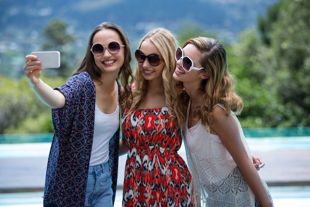 Mulheres bonitas tomando uma selfie na piscina