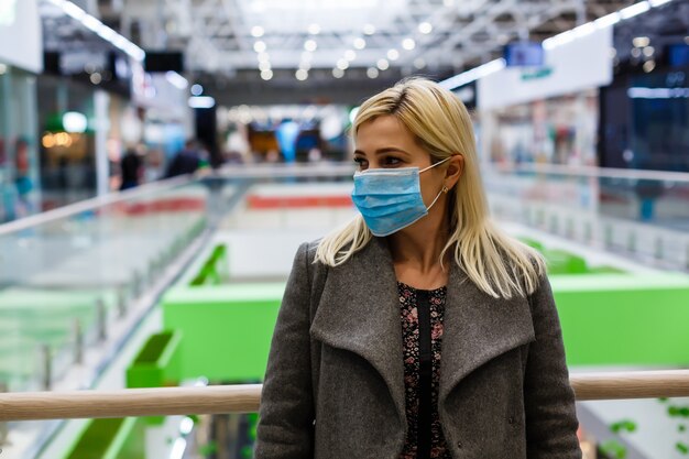 Mulheres bonitas usando máscara de proteção contra poeira em shopping center, foco seletivo.