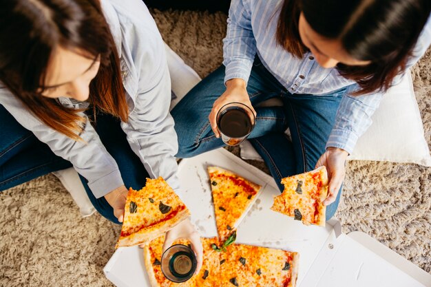 Mulheres casuais que gostam de pizza com bebidas