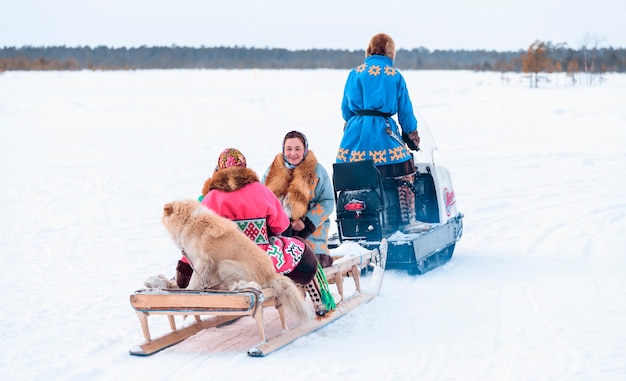 Foto mulheres com cachorro em narts com snowmobile. feriado do dia dos povos renas do norte.