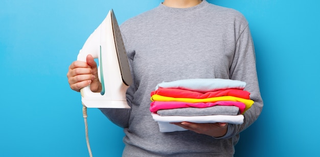 Mulheres com ferro elétrico e pilha de roupas nas mãos. Conceito de trabalho doméstico.