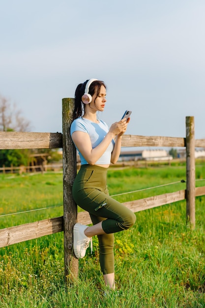 Mulheres com fones de ouvido descansam após o treino esportivo, jovens mulheres em trajes esportivos ouvindo música