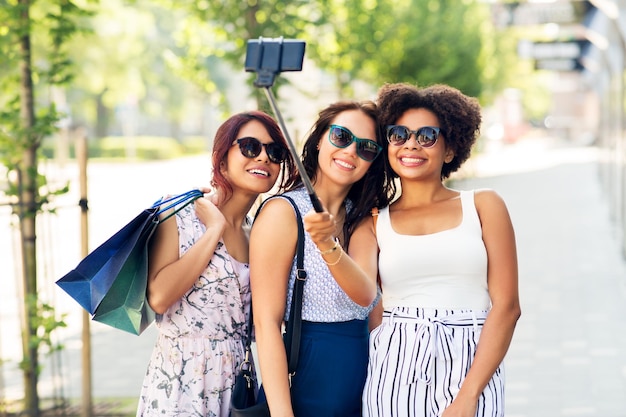 mulheres com sacos de compras tirando selfie ao ar livre