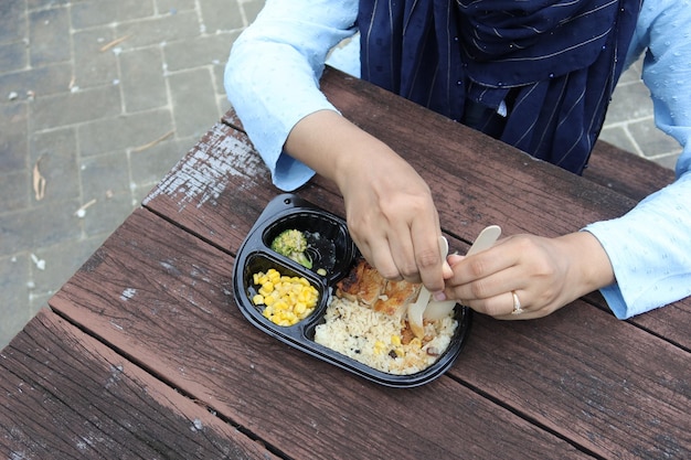 Mulheres comendo arroz de frango em um pacote para viagem no banco do parque