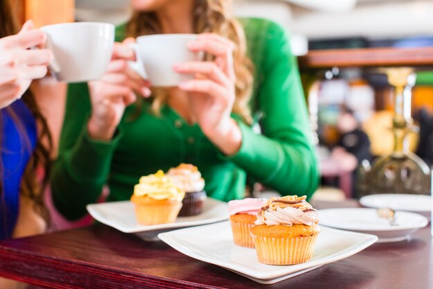 Mulheres, comendo, muffins, enquanto, café, bebendo