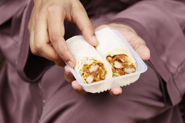 Mulheres comendo urdidura de frango sentada no banco do parque tiram o conceito de comida