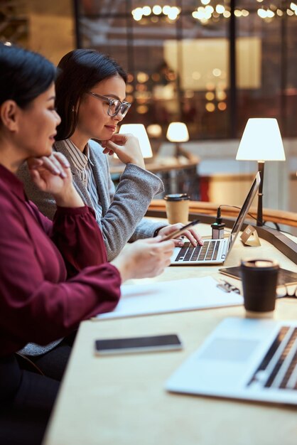 Mulheres concentradas olhando para a tela de seu laptop