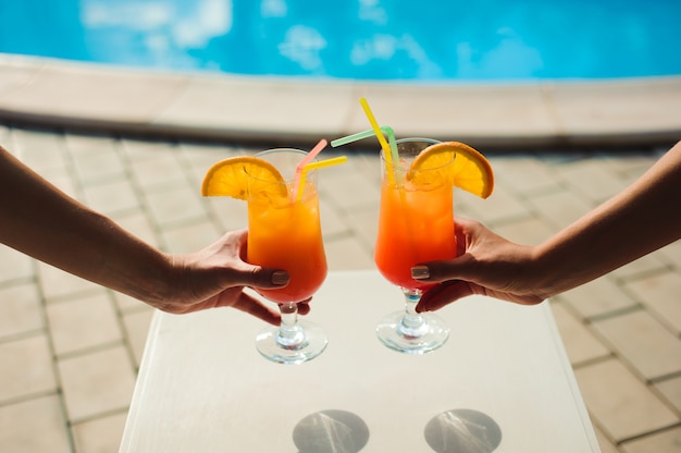 Mulheres de biquíni na piscina relaxante com suco, belas mulheres bonitas descansando em férias na temporada de verão na piscina.